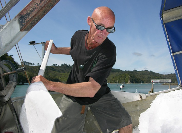 Fisherman shovels ice in his boat